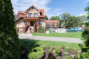 Et hotel med rødt tegltag, en balkon og et skilt der siger "Villa Areska".