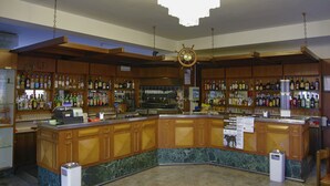 Een bar met houten kasten, een marmeren toonbank en diverse flessen.