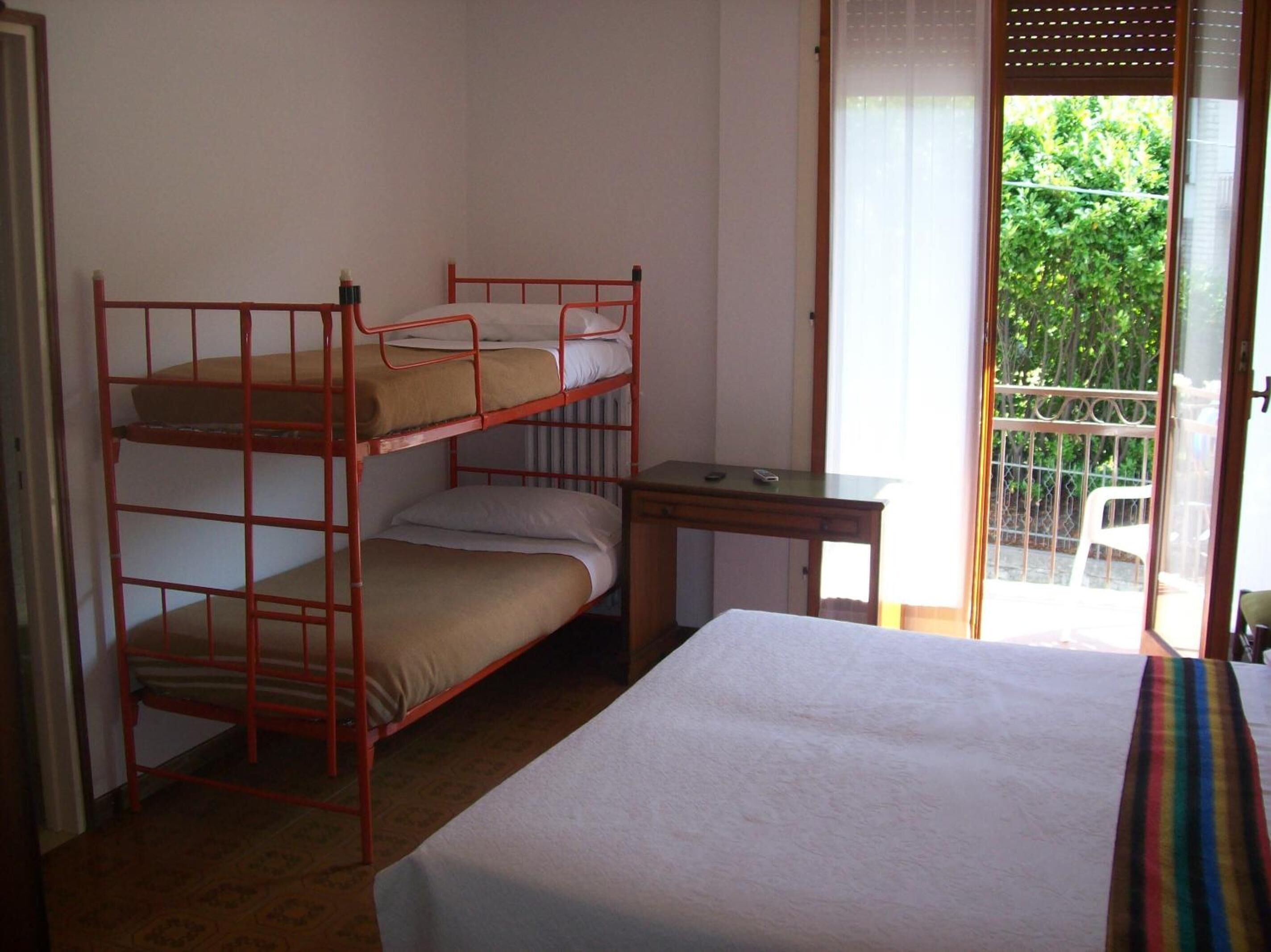 A dormitory room with bunk beds, a desk, and a bed.