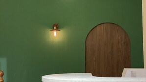 Un mostrador de recepción con tapa de madera y una pared verde al fondo.