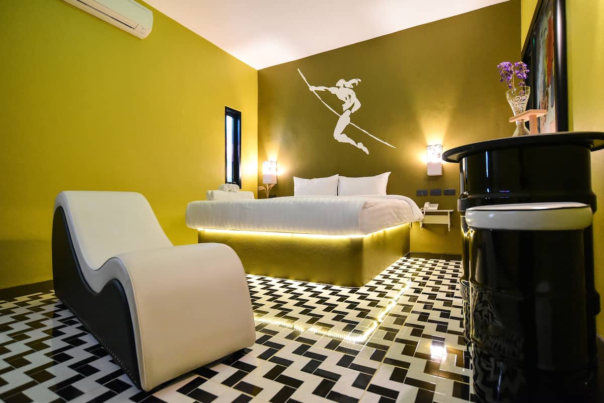 A hotel room with a bed, a massage chair, a black coffee machine, and a wall-mounted air conditioner.