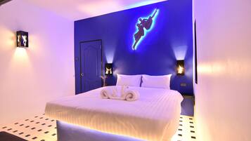 Habitación de hotel con una cama grande, una pared azul decorativa e iluminación empotrada.