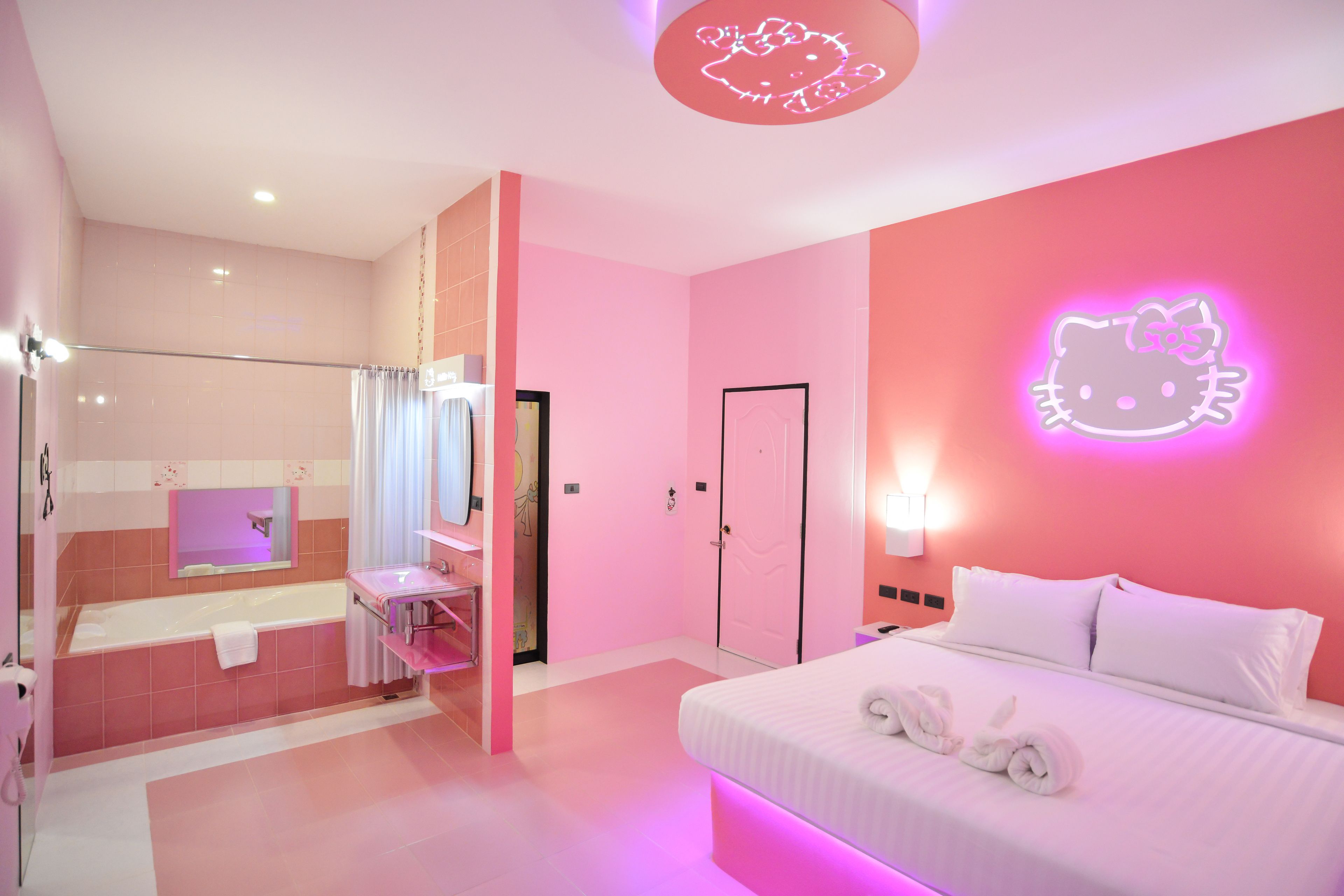 Et rosa indrettet hotelværelse med seng, badeværelse og bruseområde.