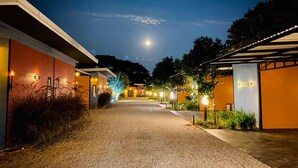 A pathway leading to a building with multiple rooms, each illuminated by exterior lights. - Bed Villa Resort Chaing Rai (Chiang Rai)