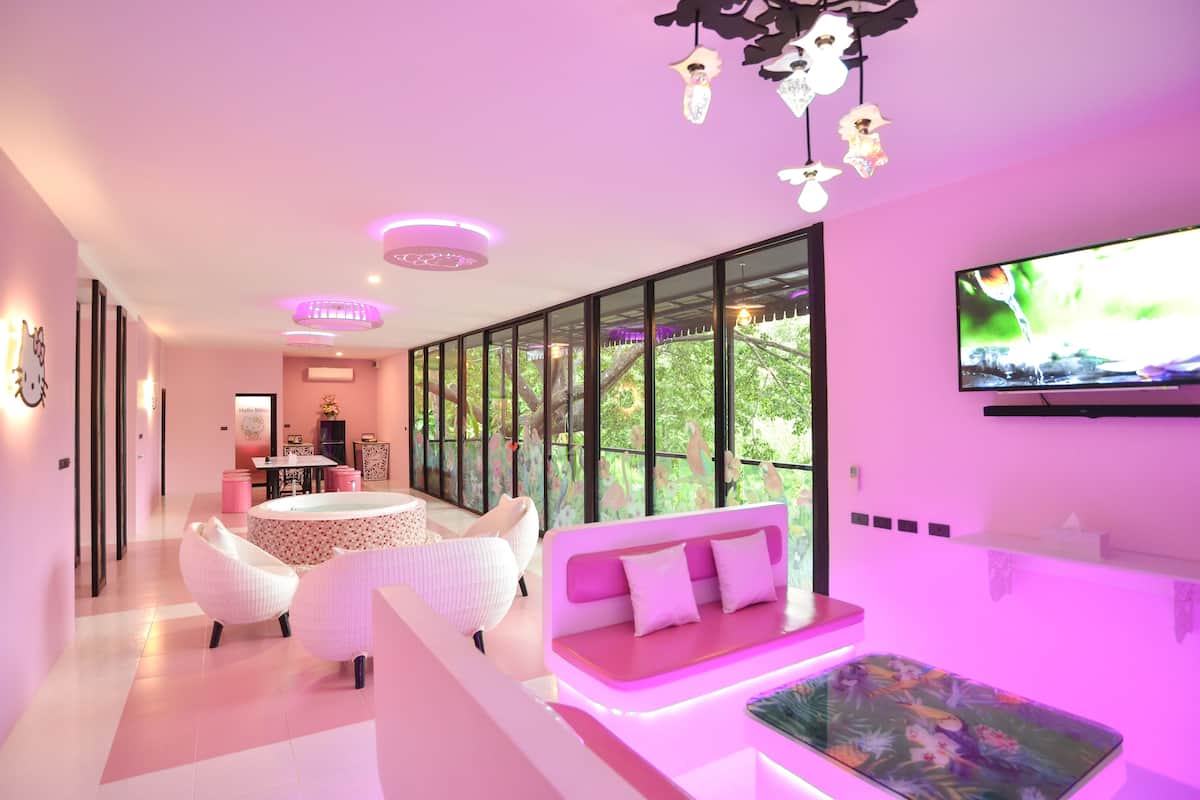 A modern interior with a pink color scheme, including a sofa, a round table, and a TV mounted on the wall.