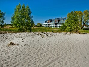 A sandy beach with a row of modern multi-story buildings in the background.