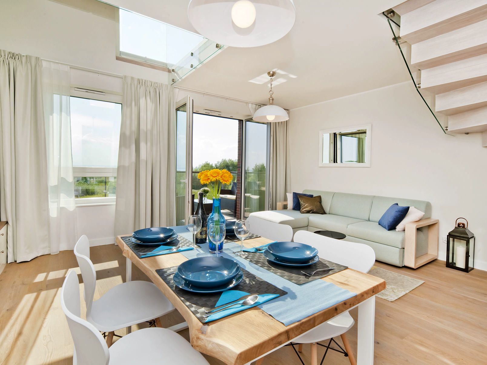 A modern dining area with a wooden table, white chairs, and blue plates.