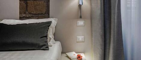 Une chambre d’hôtel avec un lit, une table de chevet, une lampe et un mur en pierre.