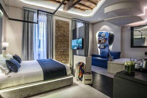 A modern hotel room with a large bed, a seating area with a sofa and armchairs, a flat-screen TV mounted on the wall, and a unique ceiling design. - Via Veneto Prestige Rooms (Rome)
