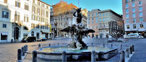 A historic fountain in a city square surrounded by classical architecture.