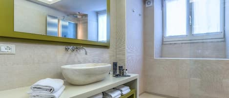 A modern bathroom with a large mirror, a white sink, and a shower area.