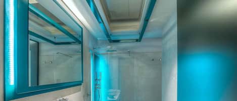A modern bathroom with a large mirror, two sinks, and a glass-enclosed shower.
