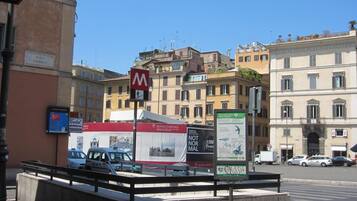 A street view with a red and white sign for a hotel, a white van, and a building with multiple windows and balconies.