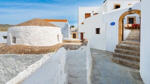 A white building with a stone staircase leading to a door with a sign above it. - Residenza Maria Lindos Villa (Rhodes)