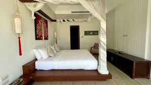 A bedroom with a canopy bed, a decorative hanging light, a wall art piece, and a bedside table with a plate. - Baan Eng Fah (Krabi)
