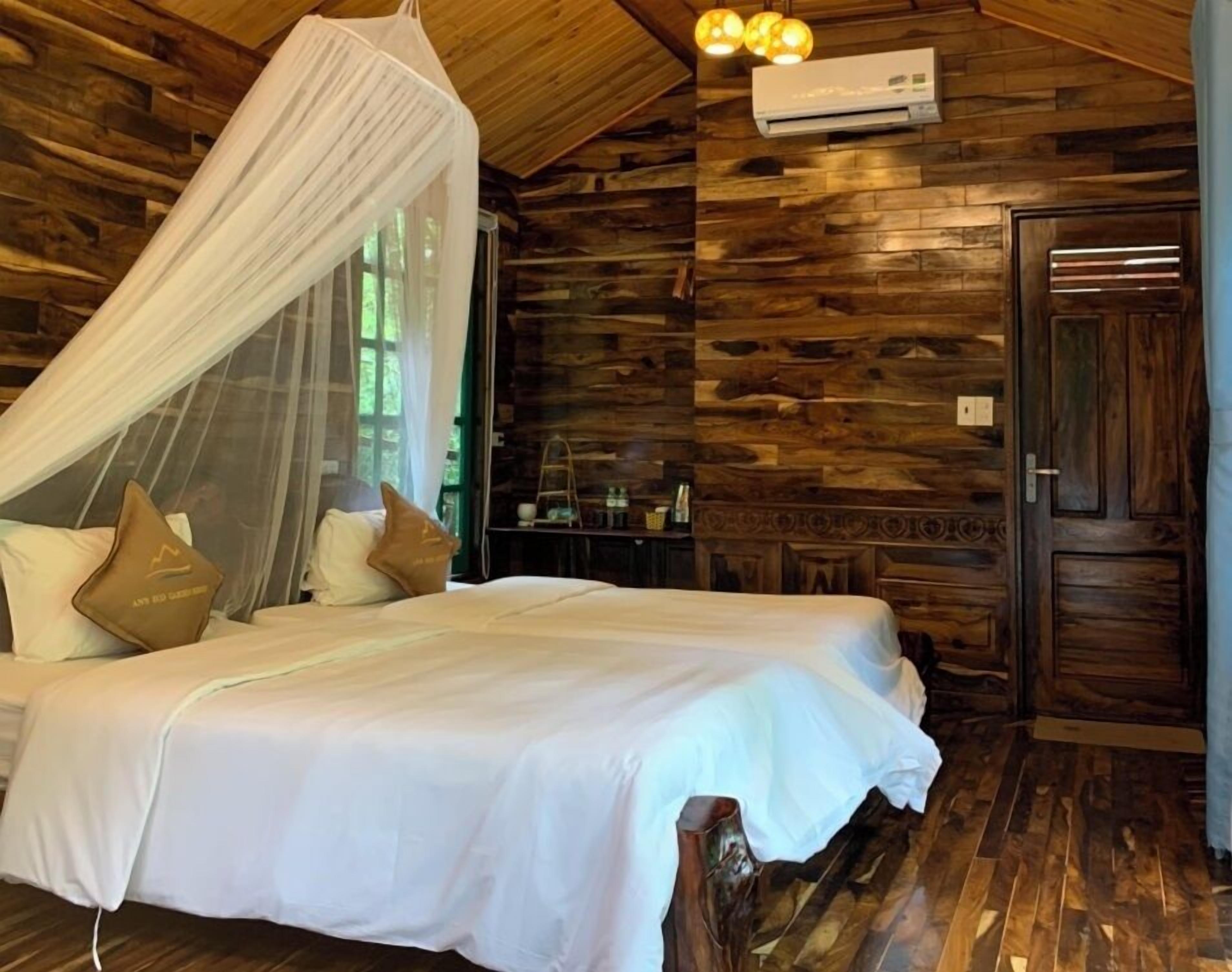 A bedroom with a canopy bed, wooden walls, an air conditioning unit, and a wooden door.