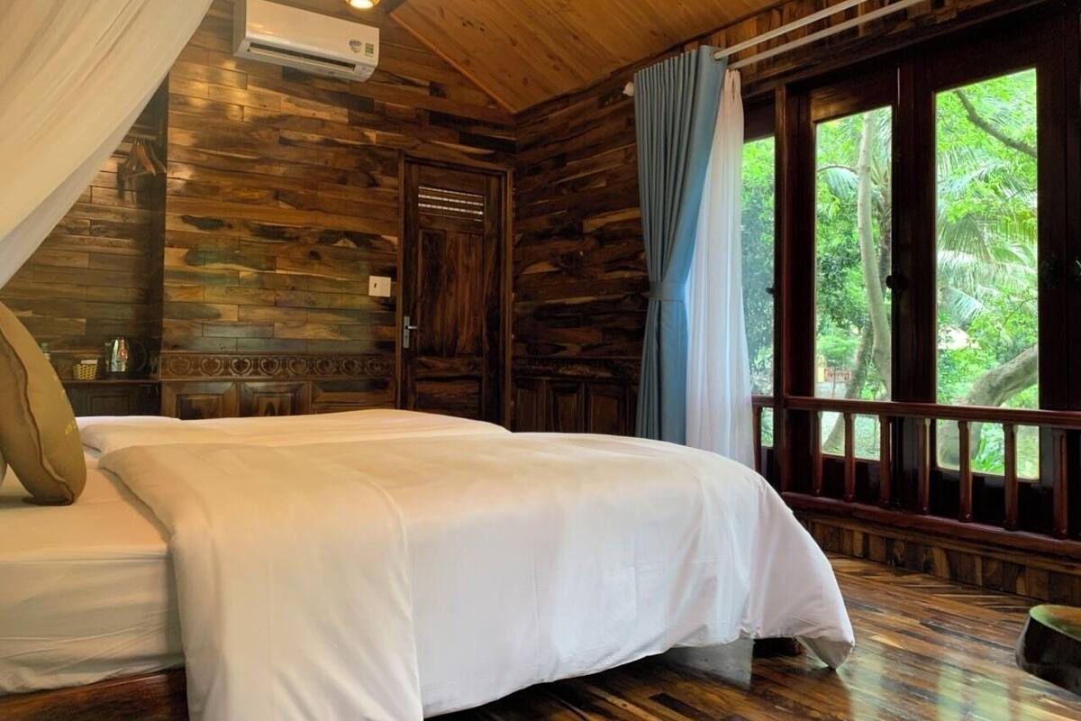 Una habitación tipo cabaña de madera con cama, cortinas y vistas al exterior.