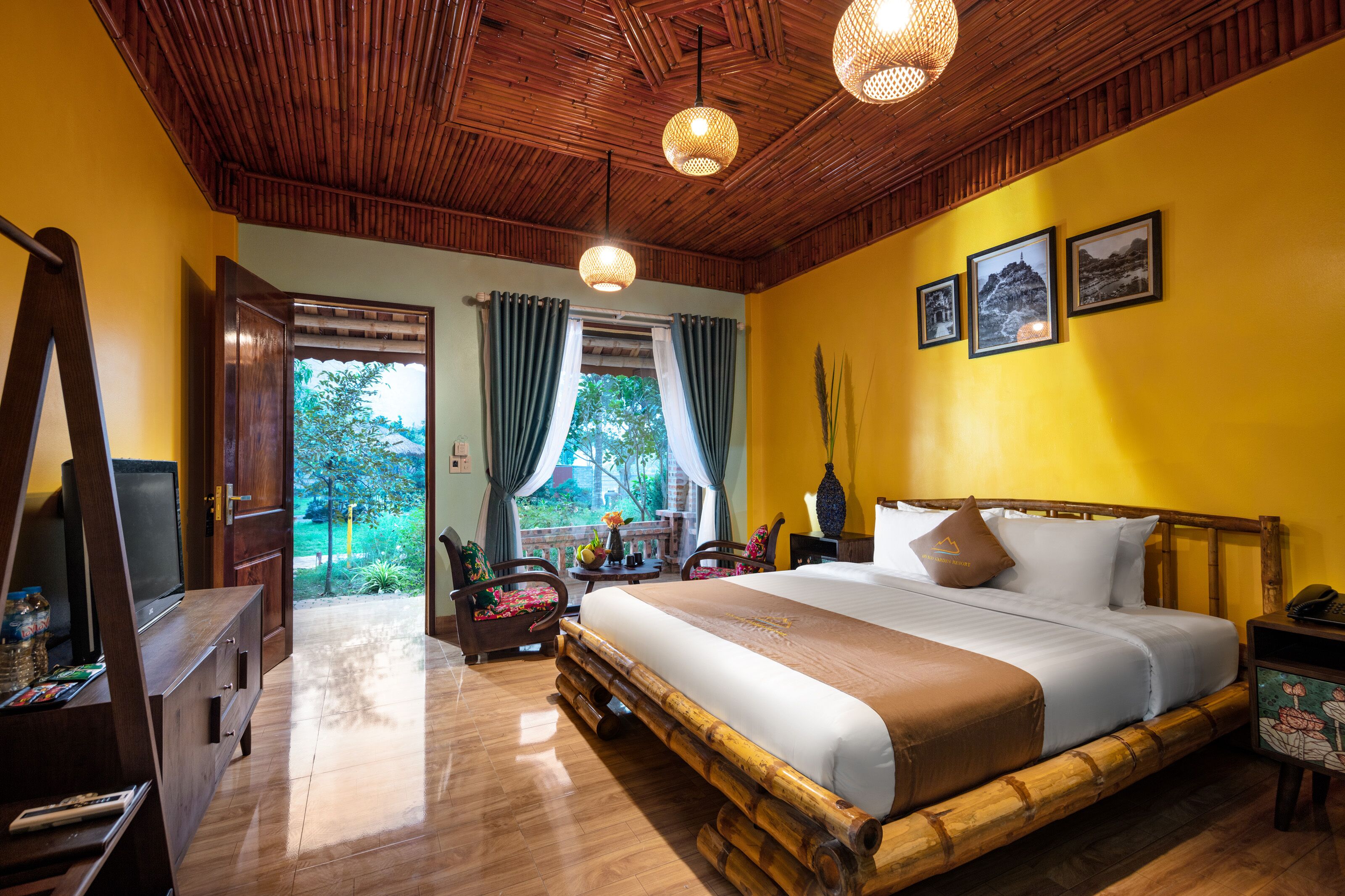 Une chambre dotée d’un grand lit, d’un plafond en bois et offrant une vue sur la verdure environnante.