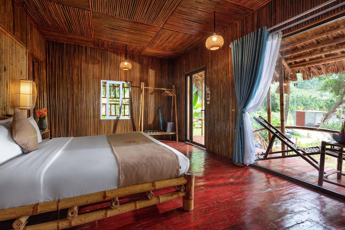 Una habitación de madera con una cama, un sillón colgante y vistas al exterior.