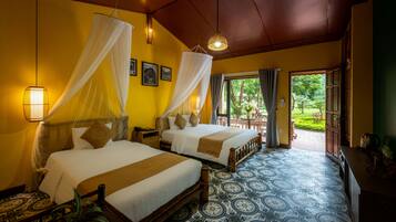 A hotel room with two beds, a large window, and a view of the garden.