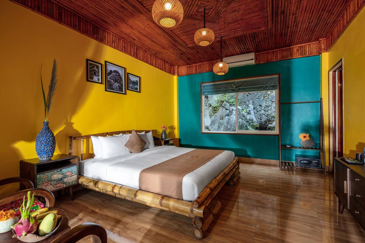 Una habitación con una cama de madera, un ventanal con vistas a árboles y un techo de madera.