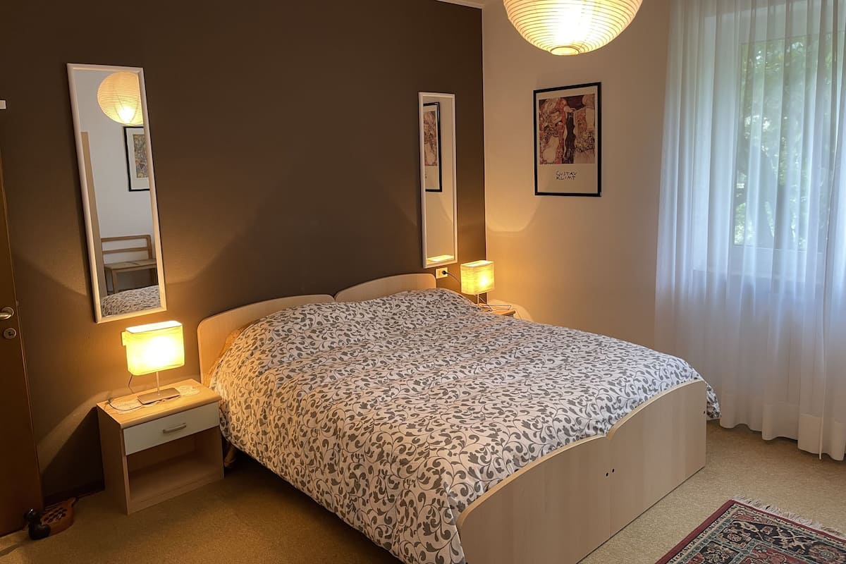 A bedroom with a bed, bedside lamps, a mirror, and a framed picture on the wall.