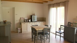 A small kitchen with a wooden ceiling, a dining table with chairs, a television, and a cabinet. - Elis' Rooms (Sernaglia della Battaglia)