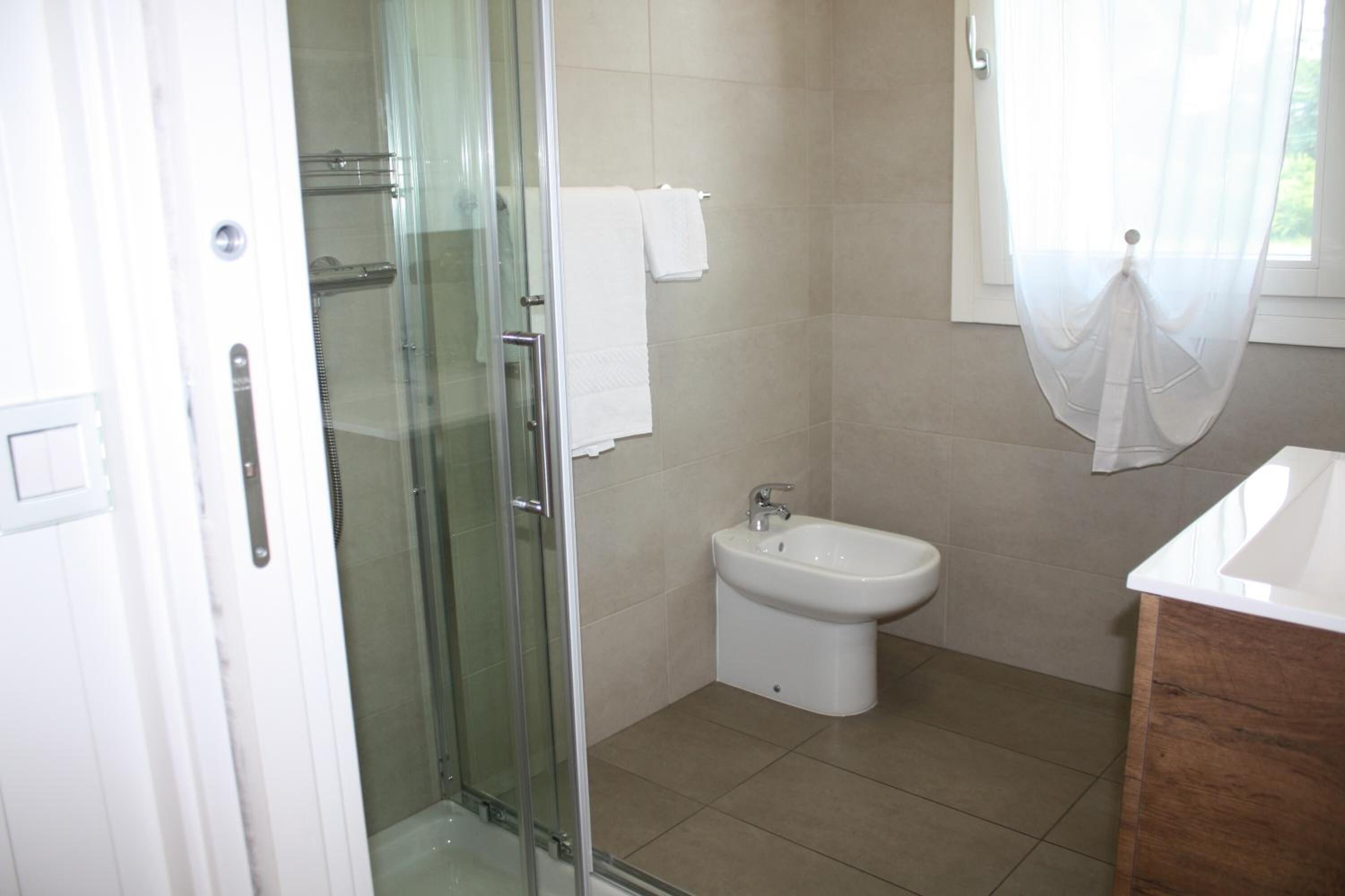 Un baño con cabina de ducha de vidrio, un lavabo blanco y un bidé.