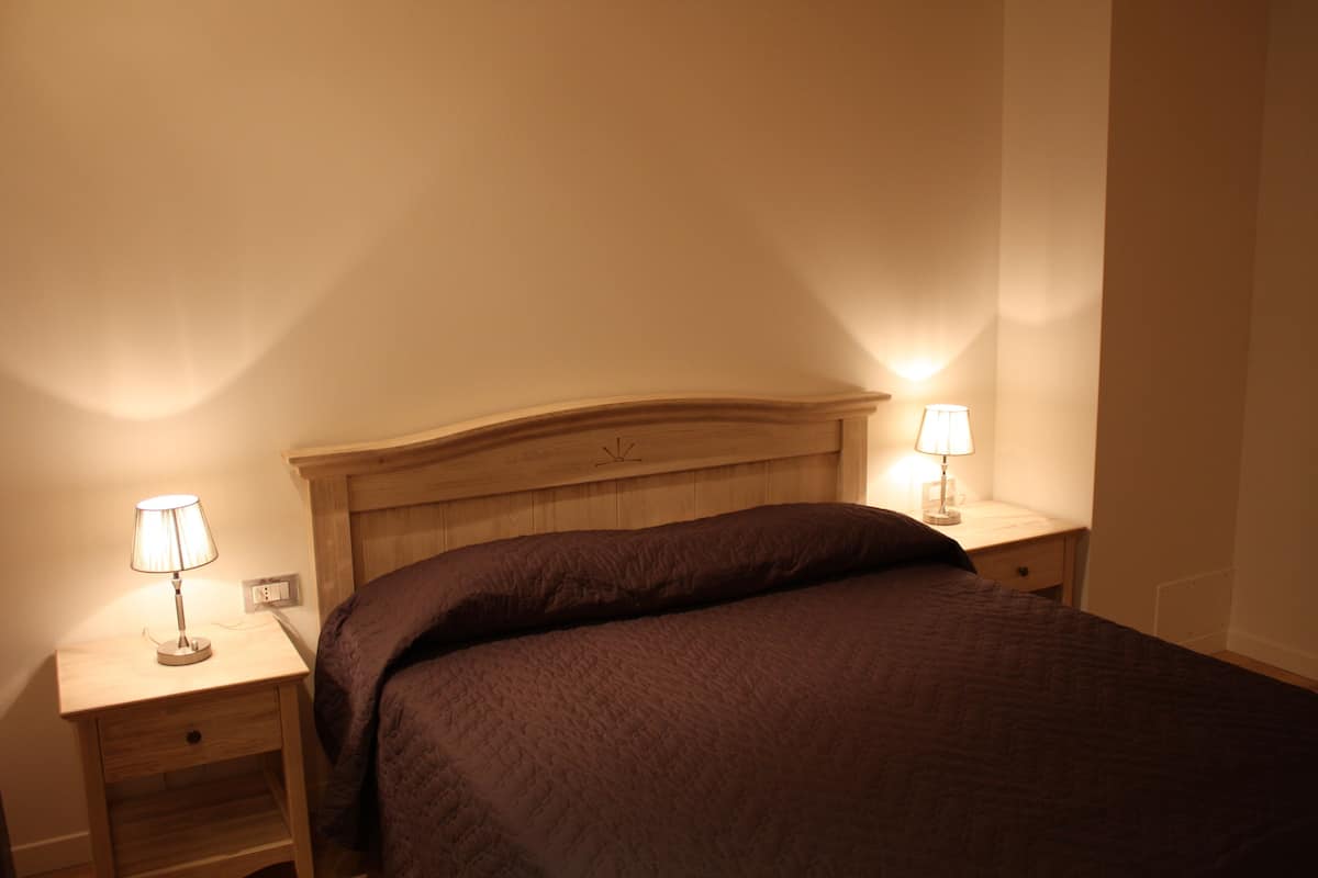 Une chambre à coucher avec un lit, deux tables de chevet et deux lampes.
