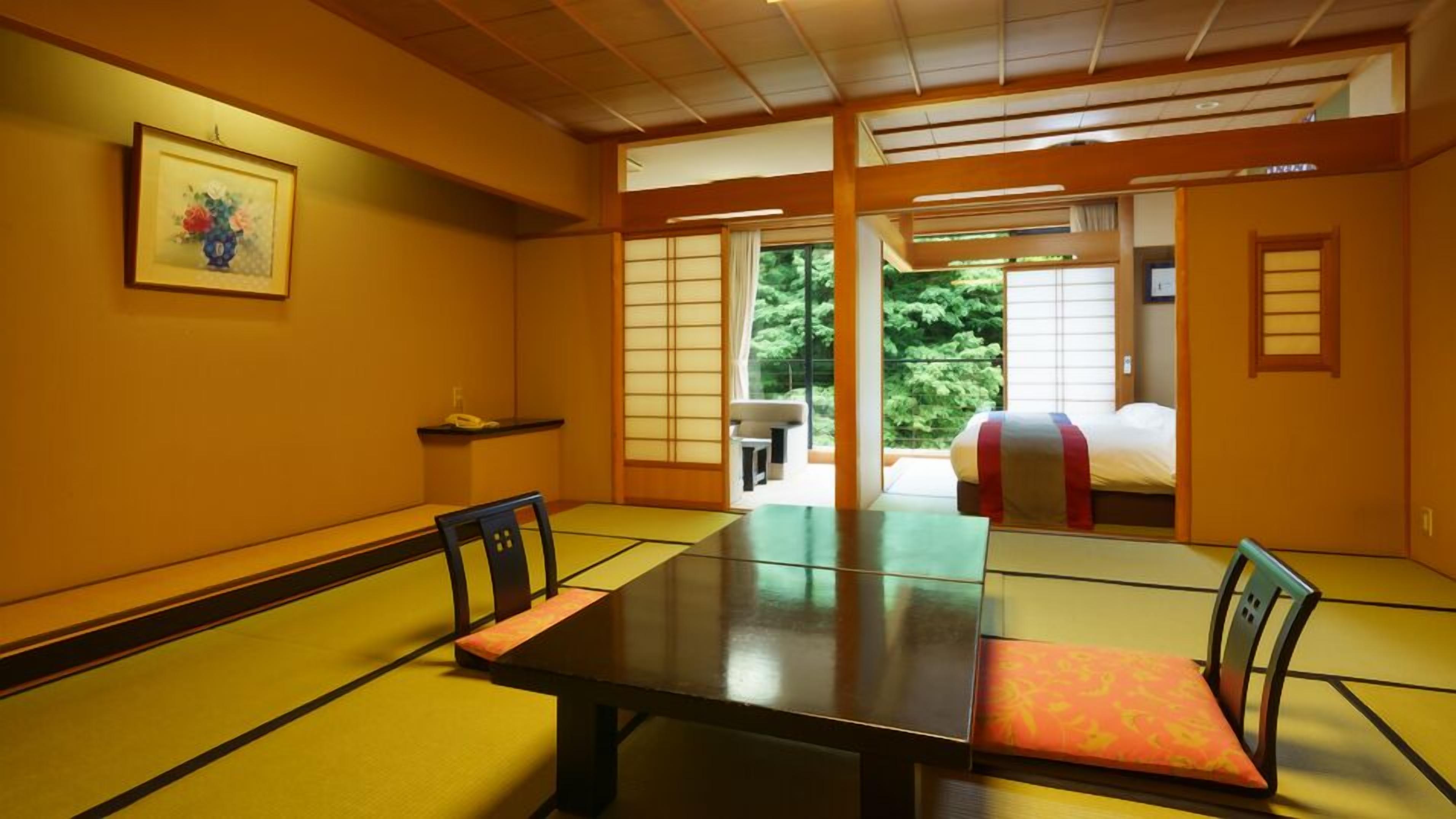 A traditional Japanese room with tatami flooring, a low table, and sliding doors leading to a balcony.