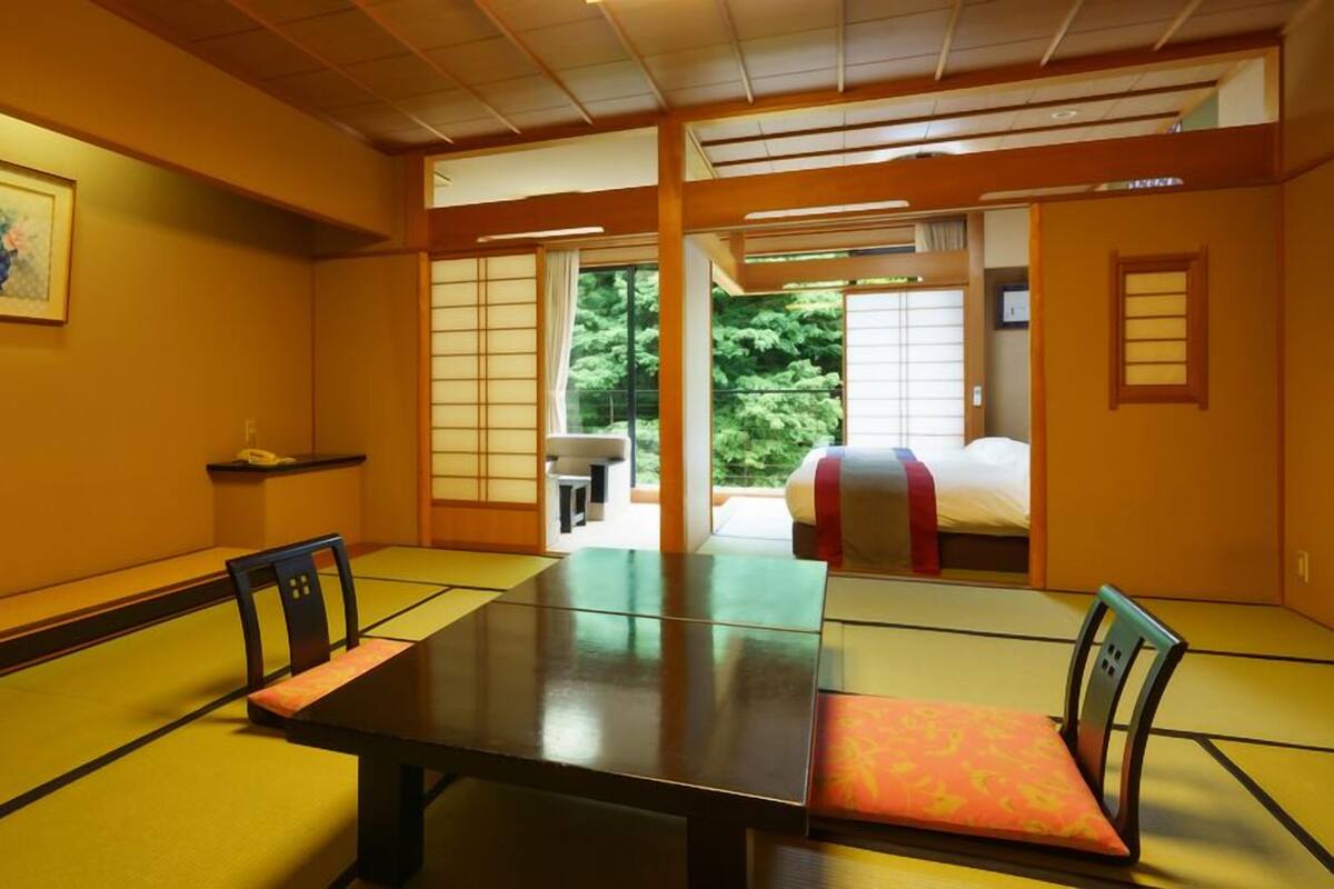 Una habitación japonesa tradicional con suelo de tatami, una mesa baja y puertas correderas que dan a un balcón.