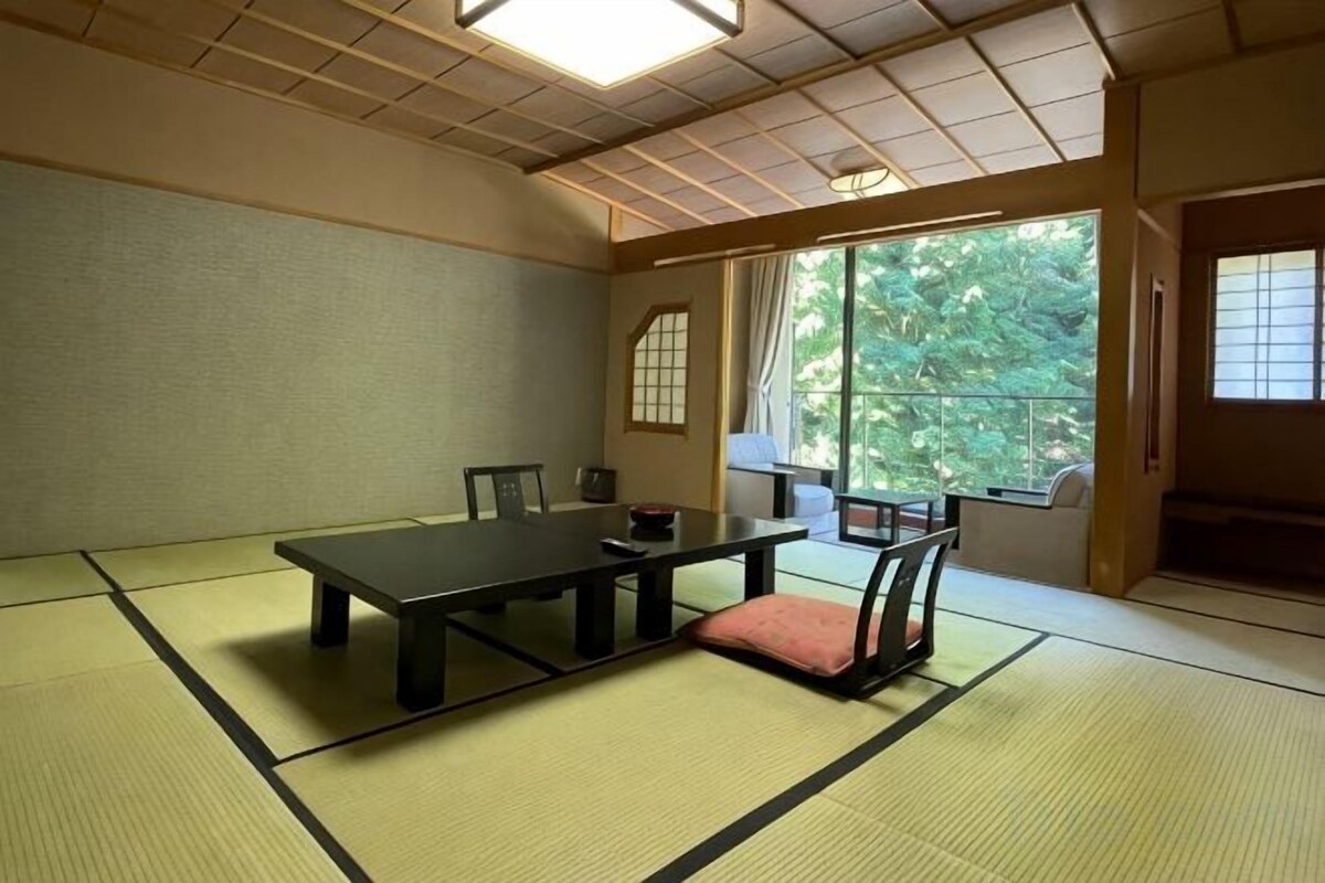 Una habitación tradicional japonesa con suelo de tatami, una mesa baja y sillas.