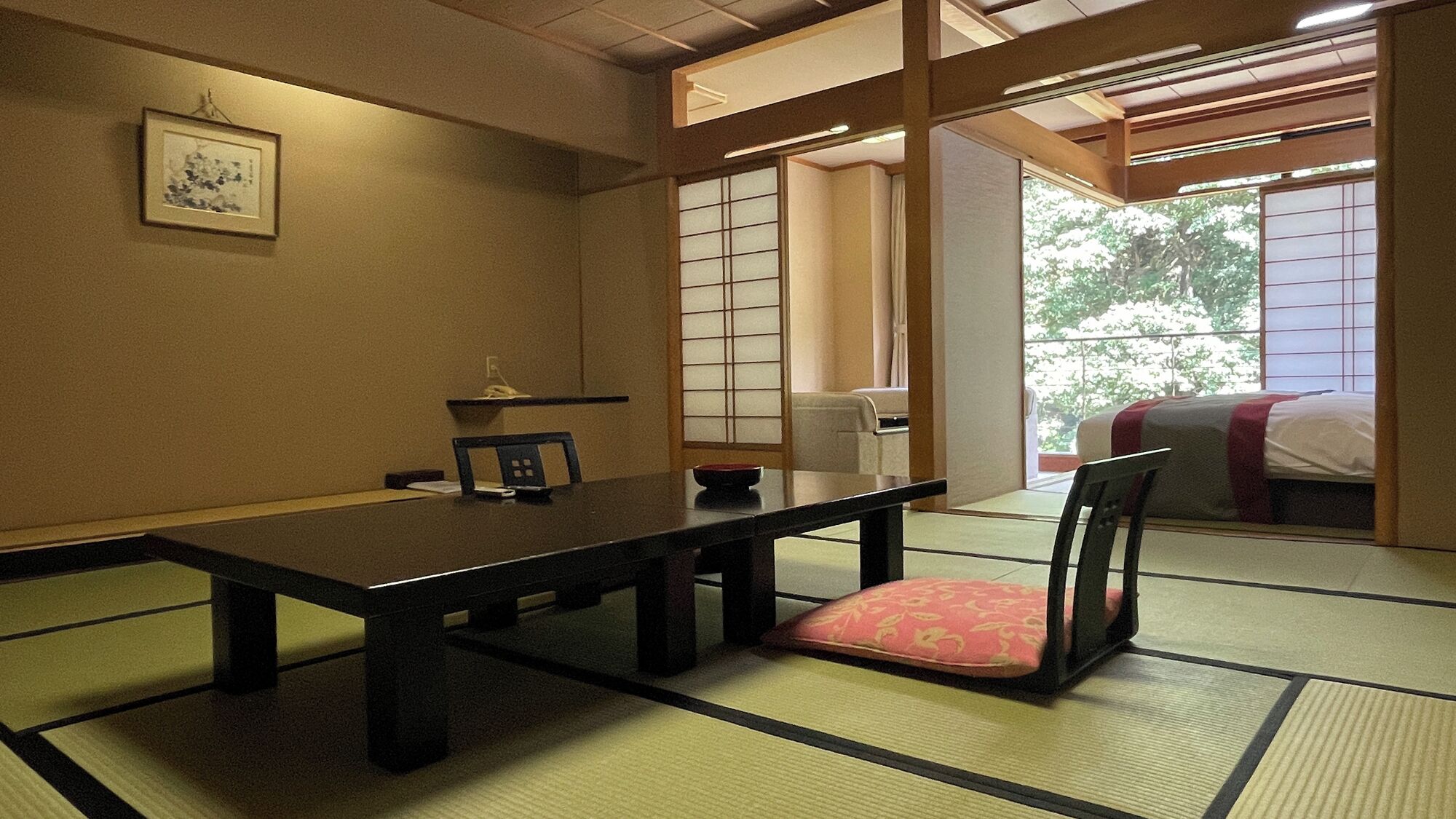 Ett traditionellt japanskt rum med tatamimattor på golvet, ett lågt bord, en stol med en kudde och skjutdörrar.