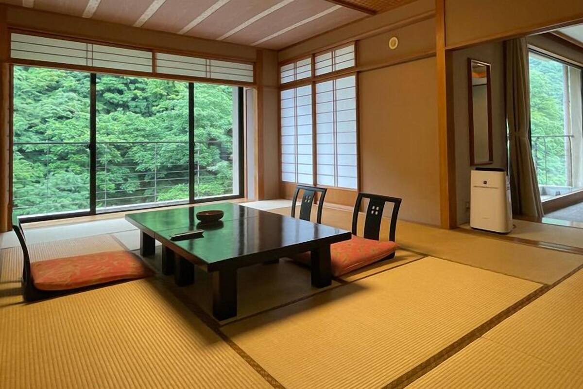 Una habitación japonesa tradicional con suelo de tatami, una mesa baja y puertas correderas.