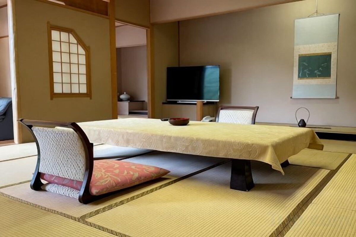 Una habitación tradicional japonesa con suelo de tatami, una mesa baja y un televisor.