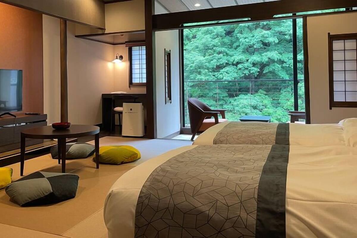 Una habitación de hotel moderna con una cama grande, un televisor, una mesita pequeña y vistas a zonas verdes.