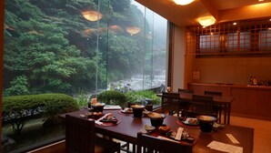 A dining area with a view of a waterfall and lush greenery. - Hotel Ogawa (Asahi)