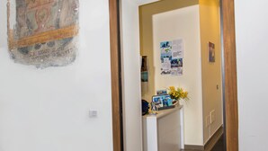 A hotel entrance with a wooden frame door, a reception desk, a wall-mounted light fixture, and a doormat with the hotel's name. - Casa Aristide (Sant'Agnello)