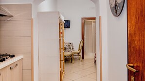A kitchen with a stove, cabinets, and a tiled floor. There is a wooden chair and a table in the background. - Casa Aristide (Sant'Agnello)