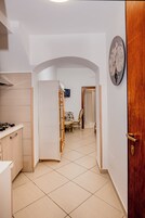 A kitchen with a stove, cabinets, and a tiled floor. There is a wooden chair and a table in the background.