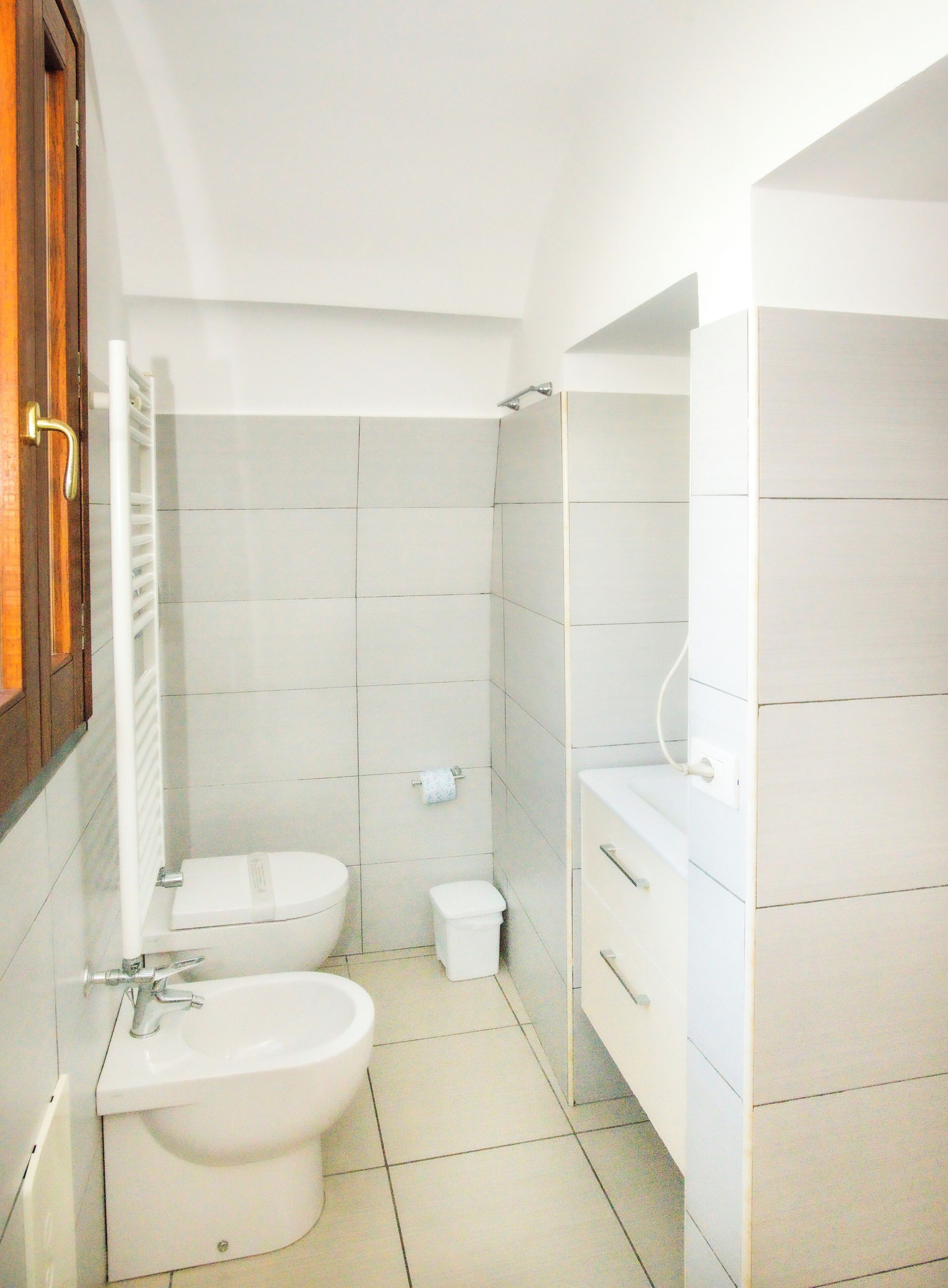 A small, modern bathroom with a toilet, bidet, and sink.