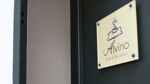 Una puerta con un letrero que dice "Alvino Suite & Breakfast" y un llamador de bronce.