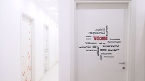 Un pasillo con una puerta que muestra una nube de palabras, con la palabra 'Welcome' en el centro, rodeada por varios idiomas.