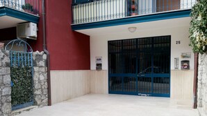 Una entrada de edificio con una verja azul, un muro de piedra y fachada de color rojo.