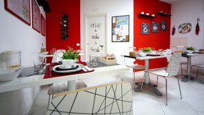 Un comedor moderno con una pared de acento roja, una puerta blanca con un cartel que dice 'RELAX & take a break' y un tablón de anuncios con varios papeles.