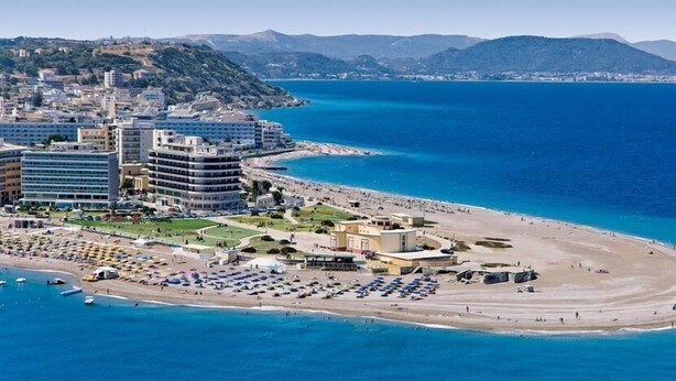 A coastal hotel with multiple buildings, a beach with sun loungers, and a view of the sea and mountains. - Alkyonides Hotel (Rhodes)