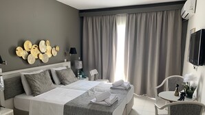 A modern hotel room with a large bed, a TV, a desk, and a chair. - Alkyonides Hotel (Rhodes)