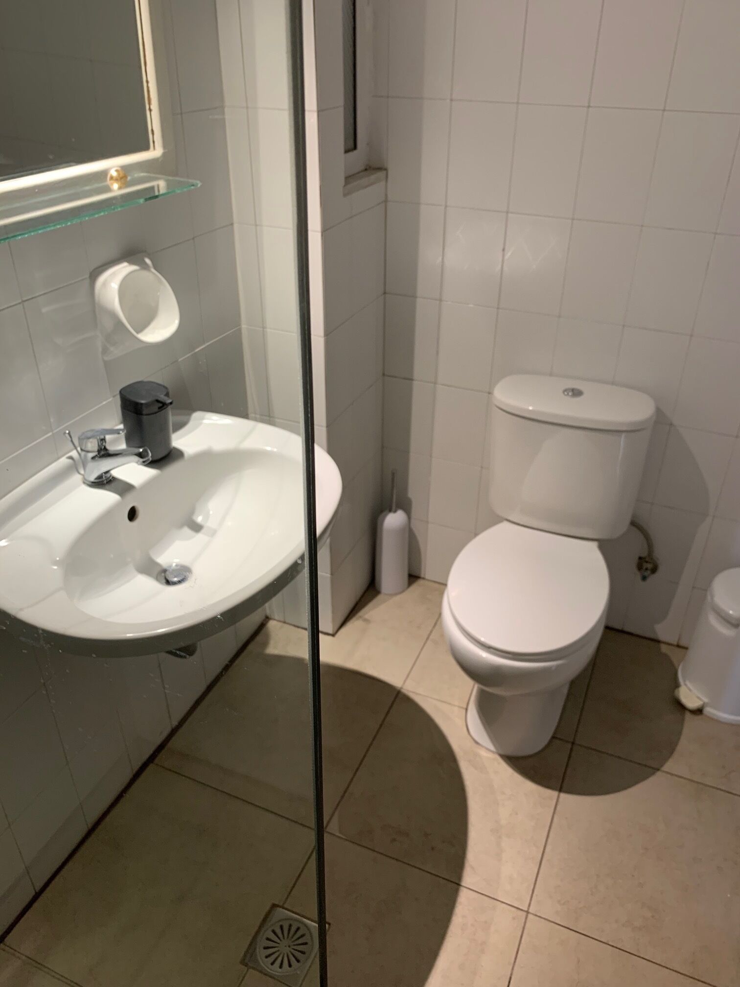 Un baño con lavamanos blanco, inodoro y cabina de ducha de vidrio.