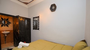 Una habitación con cama, baño con lavamanos y un espejo decorativo.