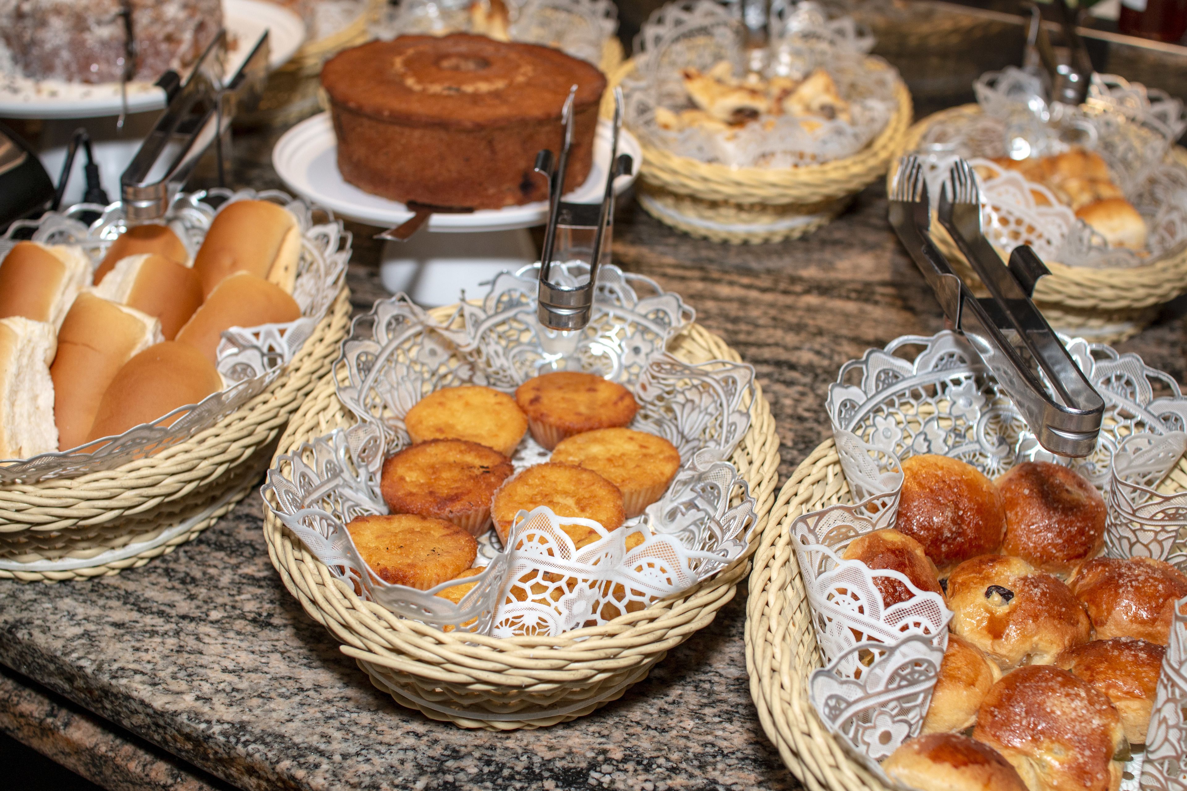 A buffet table with various food items in baskets, including bread, muffins, and pastries.